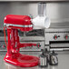 A red KitchenAid mixer with a white KitchenAid Fresh Prep Slicer / Shredder Attachment.