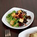 A white square melamine plate with salad, croutons, and carrots.