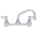 A chrome Fisher wall mount faucet with two lever handles and a swing nozzle.