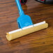 An Impact sponge mop with a blue handle on a wooden floor.