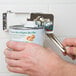 A person using a Swing-A-Way wall mount can opener to open a can of food.