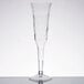 A Fineline clear plastic champagne flute with a long stem on a table.