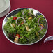 An American Metalcraft hammered stainless steel bowl filled with a salad on a table.