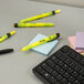 A yellow Sharpie highlighter on a post-it note on a table with a keyboard.