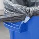 A blue Rubbermaid BRUTE recycling can with a plastic lid and a black bag inside.