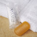 A white towel next to a PAYA orange and yellow translucent bar of soap in a small plastic bag.