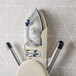 A white ironing board with an ironing board holder attached to it.