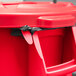 A red Rubbermaid BRUTE trash can with black handles and a black bag inside.