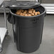 A Rubbermaid BRUTE 55 gallon black trash bin full of potatoes.