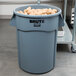 A Rubbermaid BRUTE 44 gallon gray trash can filled with potatoes.