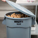 A person putting potatoes in a Rubbermaid BRUTE 44 gallon gray trash can.