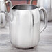 A Vollrath stainless steel water pitcher with a lid and handle.