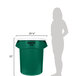 A woman standing next to a green Rubbermaid trash can with a white lid.