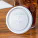 A white Cambro translucent plastic lid on a cup with a drink in it.