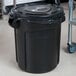 A Rubbermaid black trash can with a plastic bag on it.