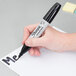 A hand using a Sharpie chisel tip permanent marker to write on a piece of paper.