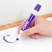 A hand holding a purple Expo dry erase marker.