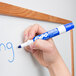 A hand writing on a white board with a blue Expo dry erase marker. Another hand holds a blue and white Expo dry erase marker.
