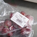 A close-up of a bag of red grapes with a white Tor Rey thermal label.