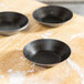 A group of Matfer Bourgeat tartlet pans on a wooden surface.