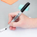 A person holding a Sharpie Ultra-Fine Point Permanent Marker over a piece of paper.