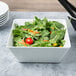 A white Vollrath melamine bowl filled with salad with tomatoes and carrots.