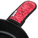 A black skillet with a red Lodge bandana handle holder on it.