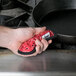 A hand holding a red bandana over a black cast iron pan.