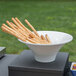 A Vollrath fluted melamine pedestal bowl filled with bread sticks on a table.