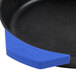 A black skillet with a blue Lodge silicone handle holder on a professional kitchen counter.