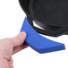 A hand using a blue Lodge silicone handle holder on a black cast iron skillet.