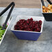 A blue and white square melamine bowl filled with cranberries and croutons.