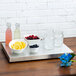 A Vollrath stainless steel cooling plate on a table with bowls of fruit and a jar of ice.