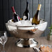 A silver Franmara double-wall stainless steel bowl with wine bottles in it on a table.