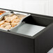 A Vollrath Cubic cold pack on a counter in a salad bar filled with food.