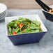 A bowl of salad with tomatoes and carrots in a Vollrath large square melamine bowl.