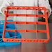 A person holding an orange plastic Carlisle glass rack extender.