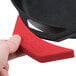 A person holding a red Lodge silicone assist handle holder on a black cast iron skillet.