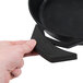 A hand using a black silicone handle holder to hold a black cast iron skillet.