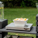 A white rectangular Vollrath cooling plate with shrimp and lemons on a table in an outdoor catering setup.