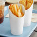 Two Choice white paper cups filled with french fries in a white container.