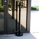 An American Metalcraft black stainless steel free standing smoker pole and base outside of a building.