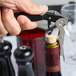 A hand using a Pullparrot waiter's corkscrew with a black handle to open a wine bottle.