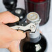 A person using a Pullparrot waiter's corkscrew with a black and silver knife to open a bottle of wine.