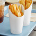 Two Choice white paper cups filled with french fries and a drink.