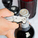 A hand using a silver Pullparrot Waiter's Corkscrew with white handle to open a bottle of wine.