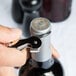 A hand using a Pulltap's Original Waiter's Corkscrew to open a bottle of wine.