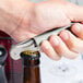 A hand using a Pulltap's Original stainless steel waiter's corkscrew to open a bottle.