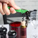 A hand using a Pulltap's Original lime green corkscrew to open a bottle of wine.