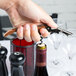 A hand using a Pulltap's copper corkscrew to open a bottle of wine.